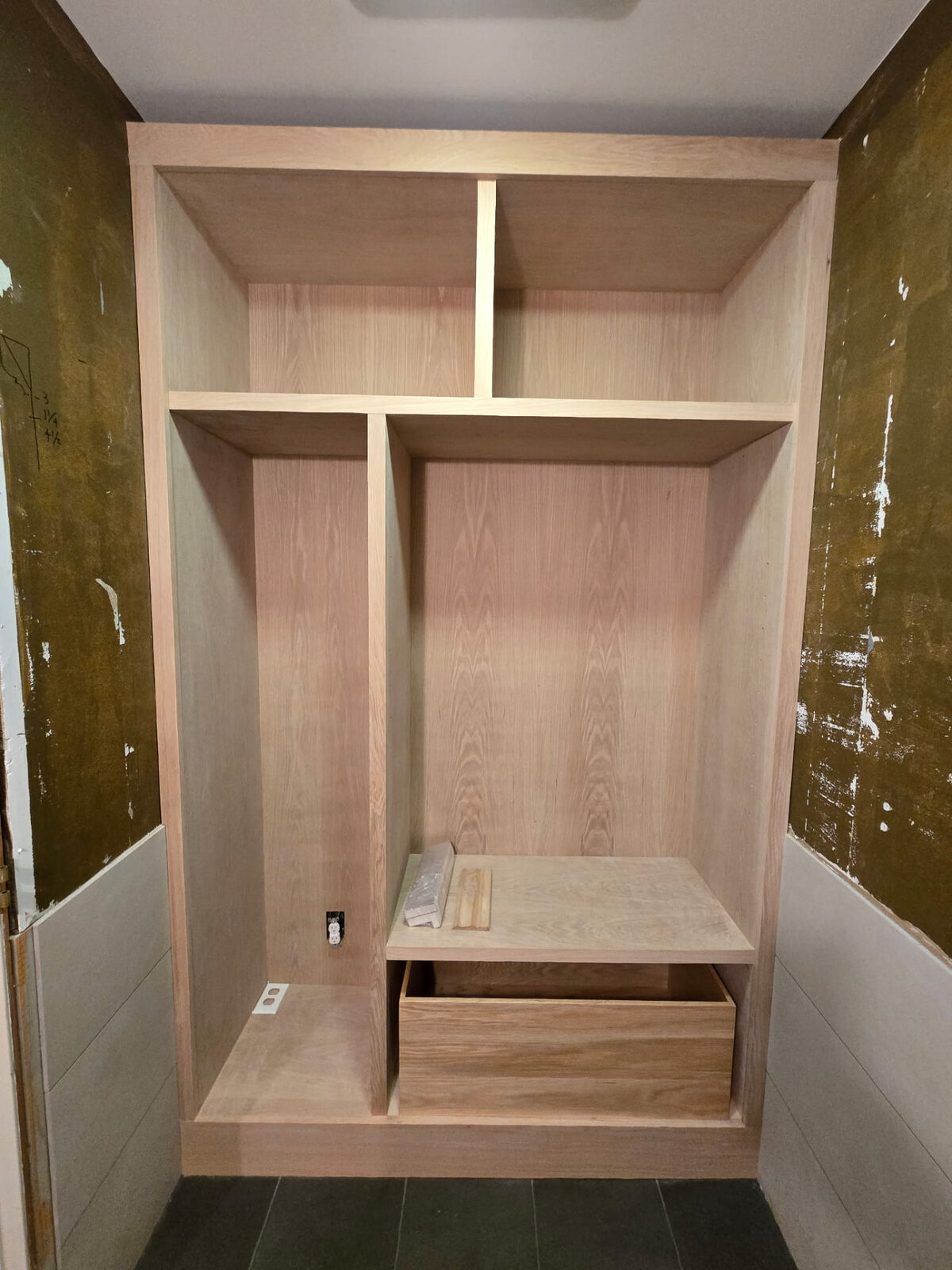Custom white oak closet during construction, showing open shelving compartments before doors were installed