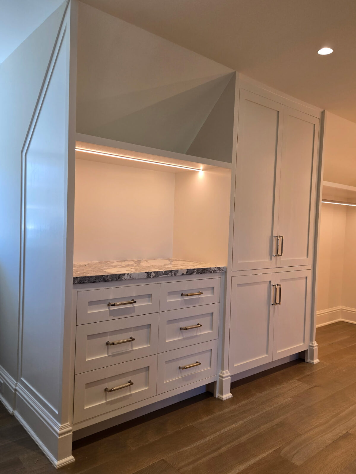 Finished white built-in cabinetry with drawers, stone countertop and integrated lighting in a Ridgefield CT custom walk-in closet