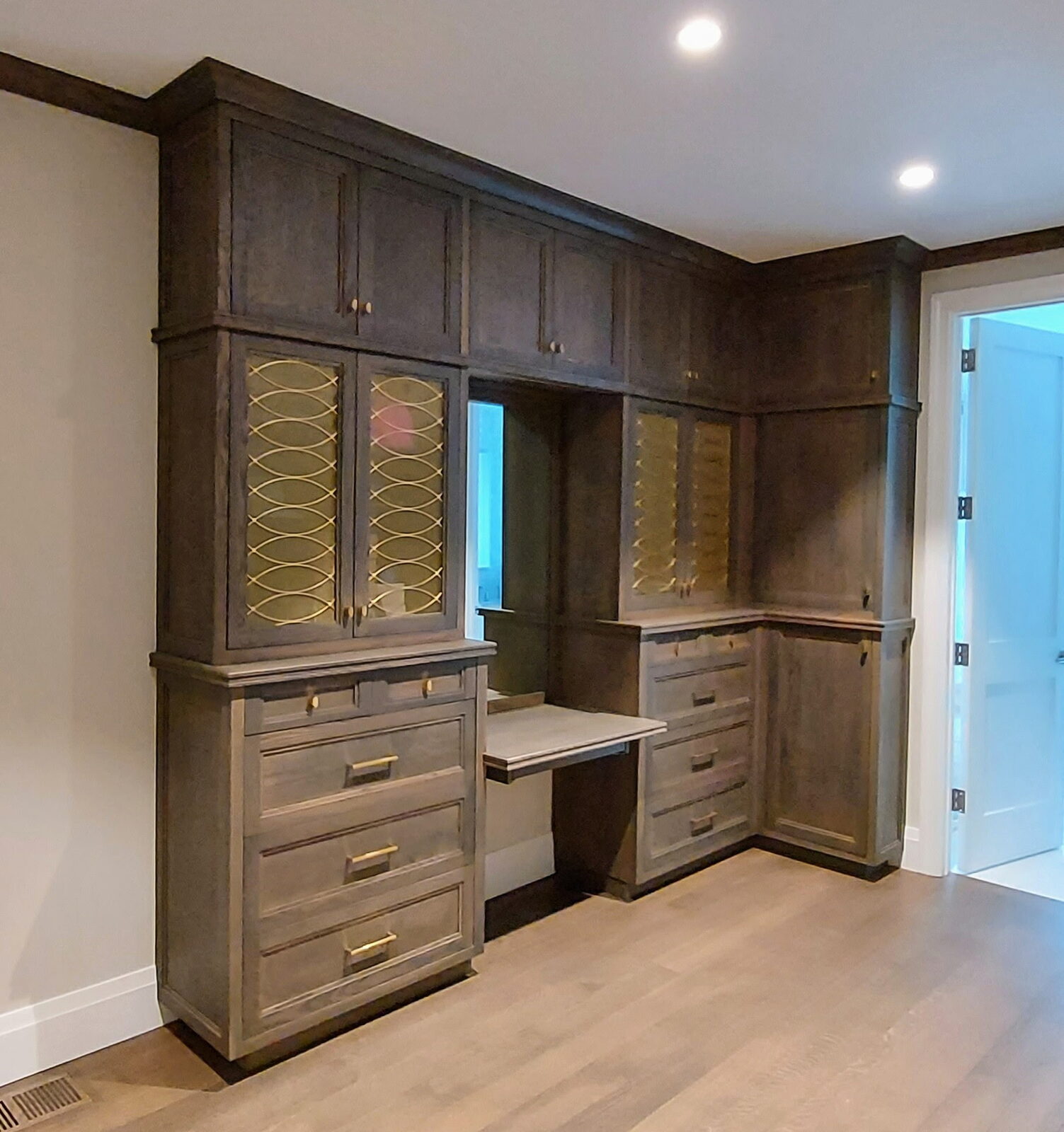 Custom built-in home office cabinetry in Ridgefield CT — completed stained built-ins with glass-front display cabinets, mirror and brass hardware