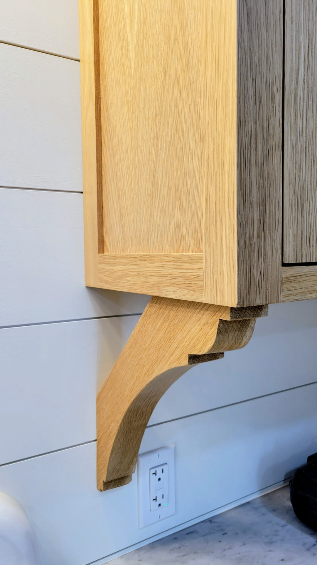 Detail of hand-shaped oak corbel supporting a wall cabinet