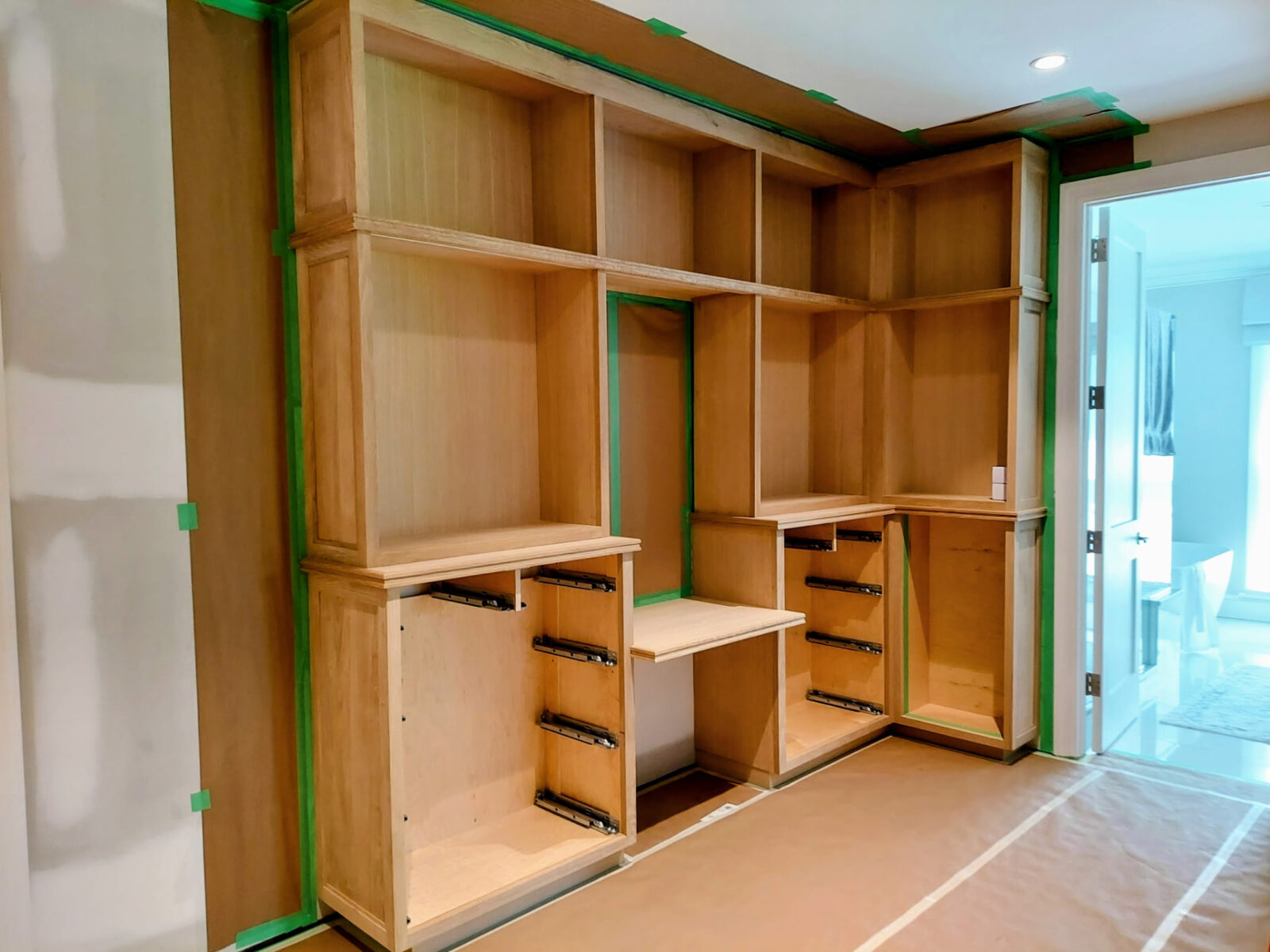 Custom home office built-in cabinetry under construction in Ridgefield Connecticut, showing unfinished cabinet boxes, drawer runners and open shelving