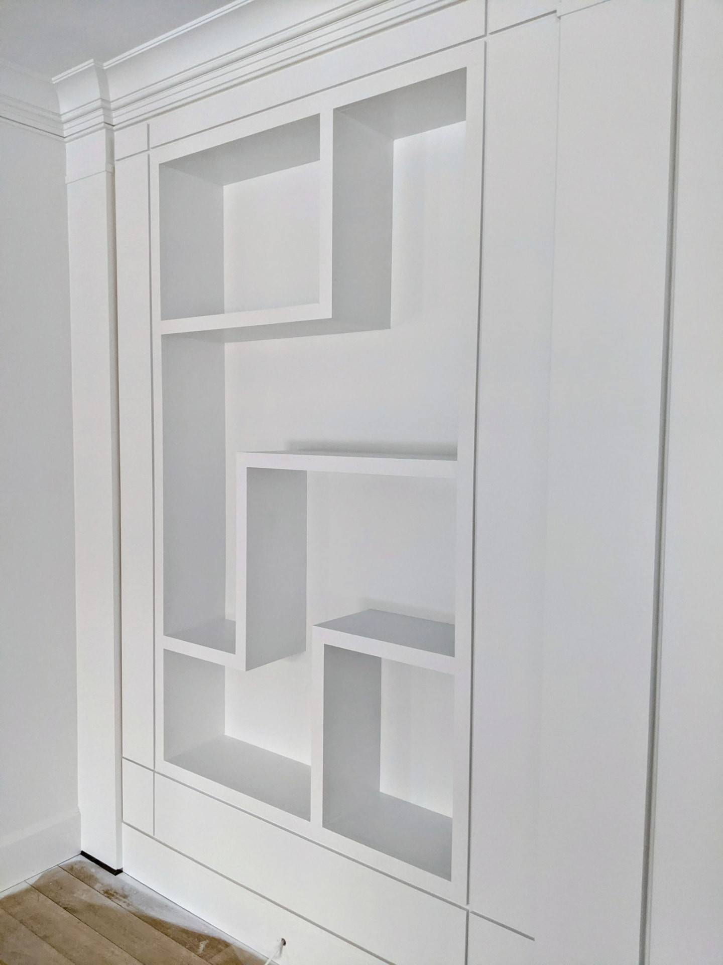 Close angled view of the painted left-hand asymmetric shelving unit and wall paneling in a Greenwich CT living room