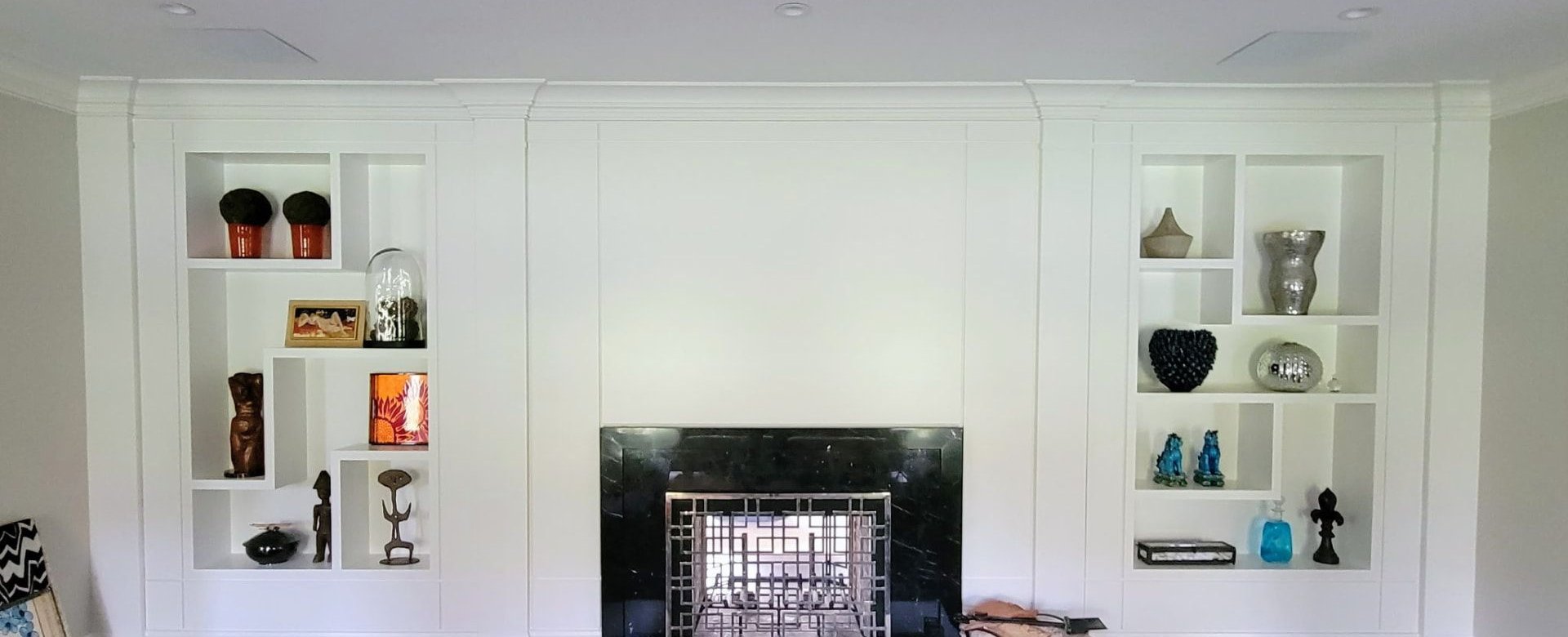 Custom asymmetric built-in shelving flanking a fireplace in a finished Greenwich CT living room by Glissmann Construction