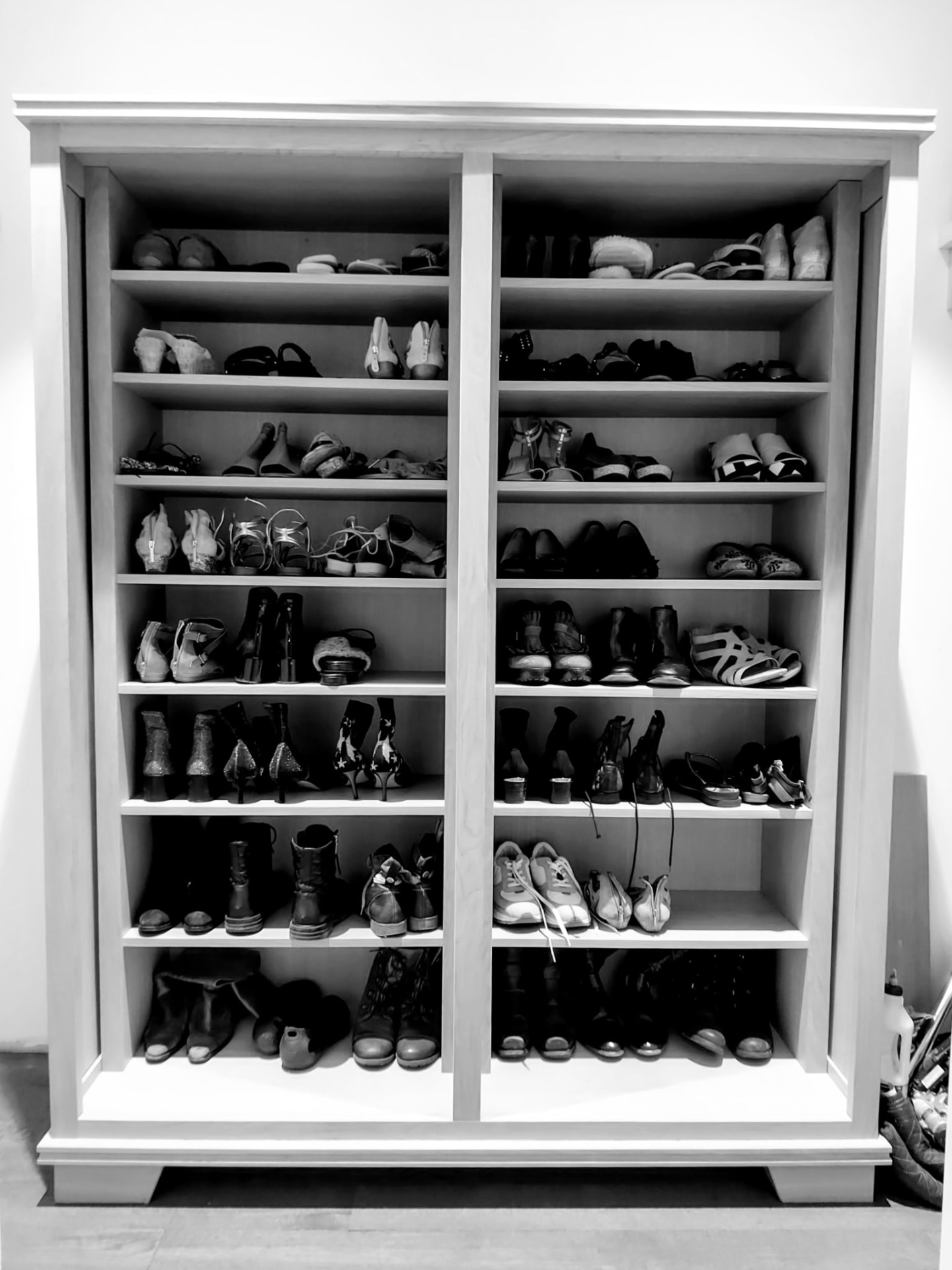 Tall white oak shoe storage cabinet with two columns of shelving in a Greenwich, CT home