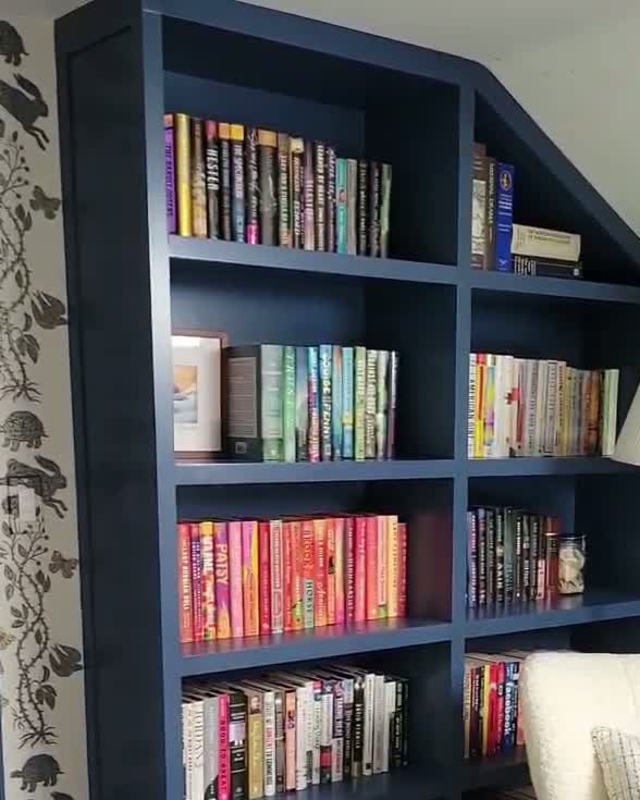 Custom navy built-in bookshelves fitted to a sloped ceiling in a Connecticut home