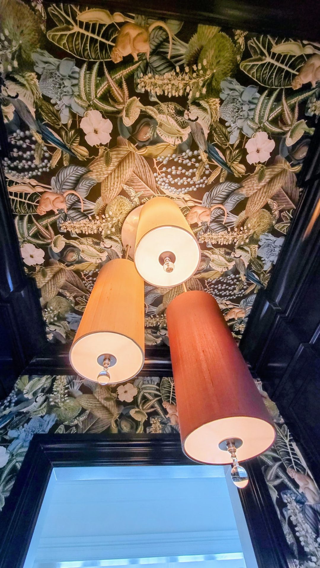 Close-up of botanical wallpaper and gloss-painted stepped crown moulding around a Ridgefield CT butler's pantry ceiling, with a three-shade pendant light