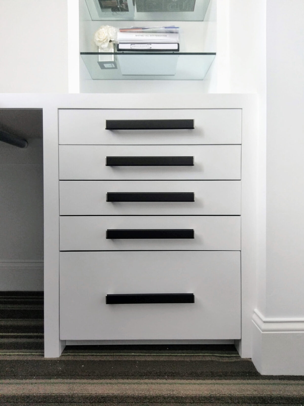 Close-up of the white built-in drawer stack with black bar pulls and glass display shelf in the Ridgefield, CT home office