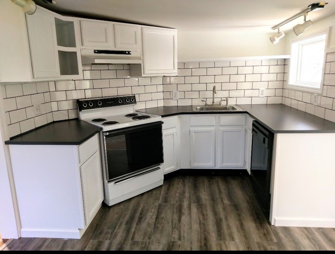 White kitchen cabinetry with a glass-front cabinet and dark countertops in Ridgefield, CT.