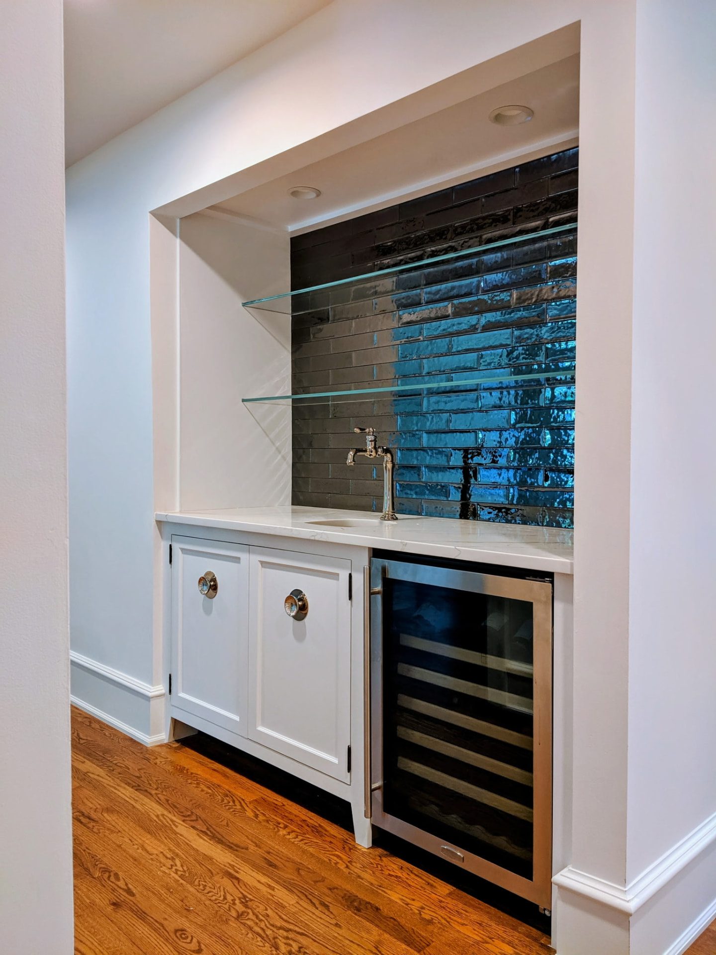 Custom wet bar cabinetry with glass shelving and dark tile backsplash in a Ridgefield, CT home